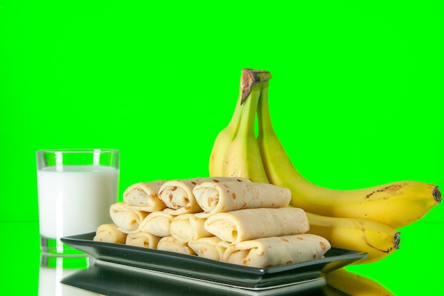 front view yummy rolled pancakes with bananas and milk on green background color fruit dessert sugar morning milk sweet cake