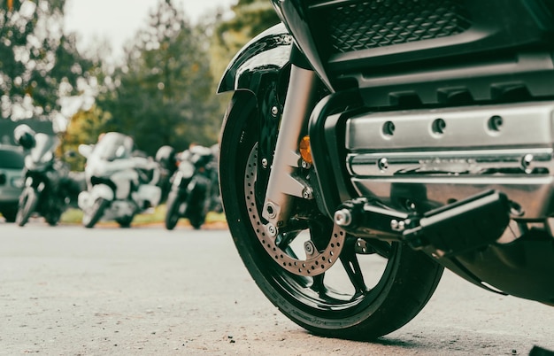 Front wheel of motorbike on asphalt road In background motorbikes