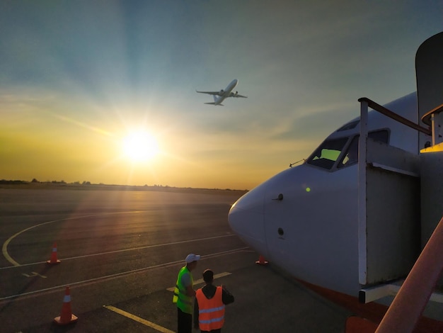 日没時に空港の滑走路に立っている白い民間航空機の正面背景の飛行機のコンセプトで離陸する旅客機