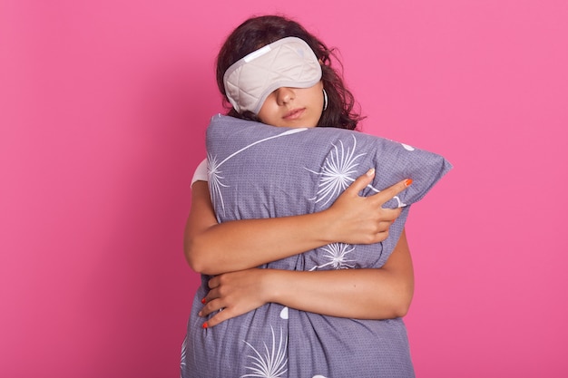 Front wiev of good looking young woman leans on gray pillow