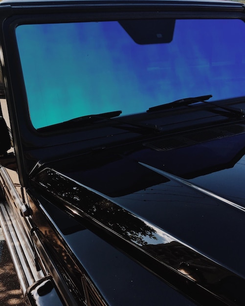 Foto vetro anteriore di suv nero con un riflesso blu del cielo