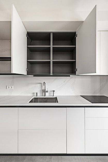Frontaal beeld van een moderne design keuken met strakke greeploze kasten met grijze interieurs en marmeren werkbladen