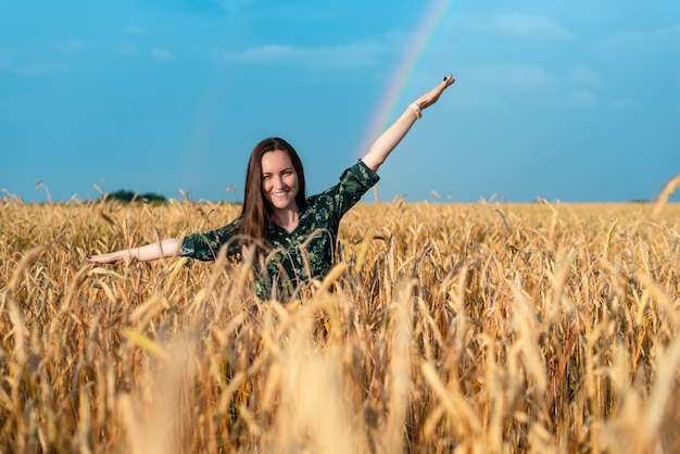 Frontaal portret van een vrouw in een veld met roggeaartjes op een regenboog