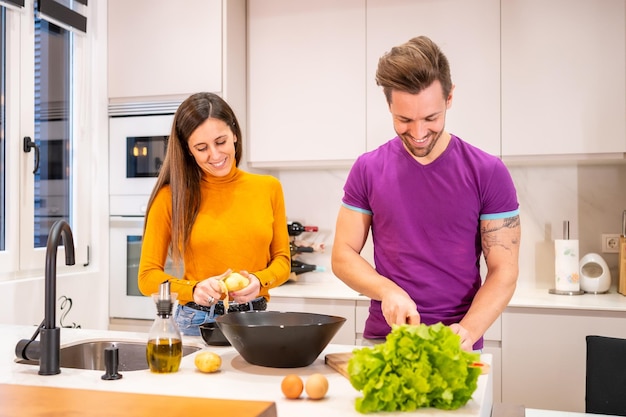 Frontal view of a Ccuple preparing a salad together at home