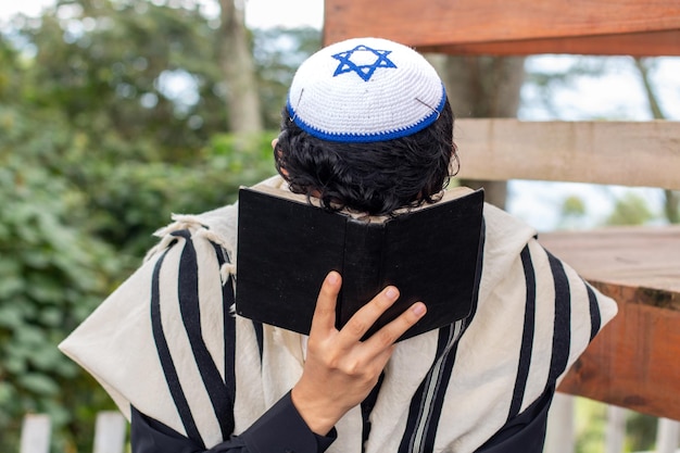 Photo frontal view of a jew praying to his god and curving his face with a siddur