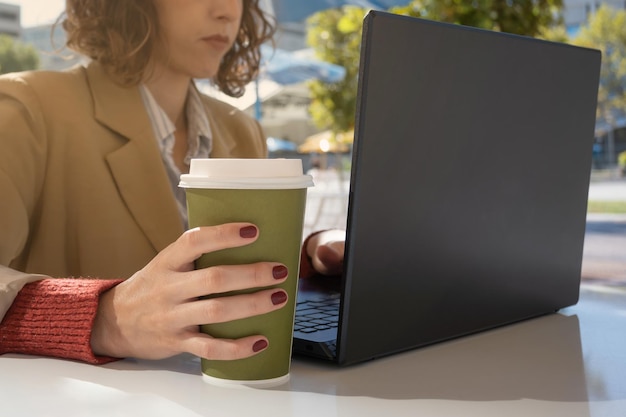 Frontal view of woman working on computer and drinking coffee, with copy space