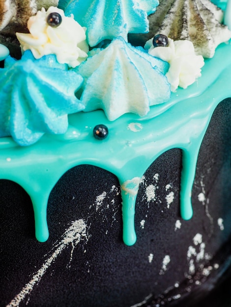 Frosted black painted cup cake with blue turquoise dripping