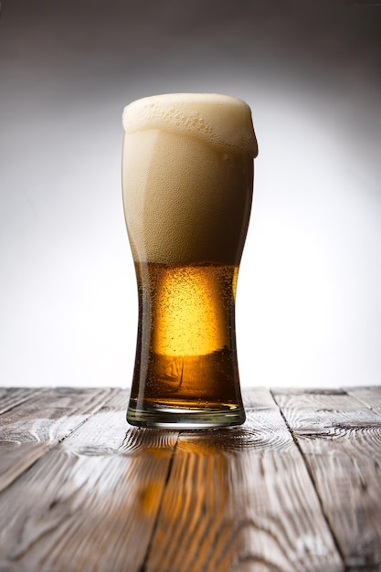 Frosted glass of light beer on wood table