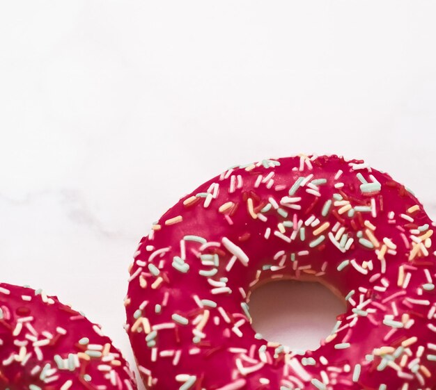 Frosted sprinkled donuts sweet pastry dessert on marble table background doughnuts as tasty snack top view food brand flat lay for blog menu or cookbook design