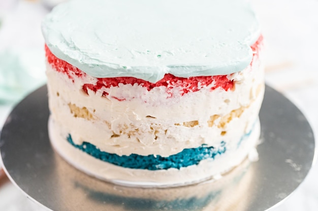Frosting round vanilla cake with buttercream frosting for July 4th celebration.