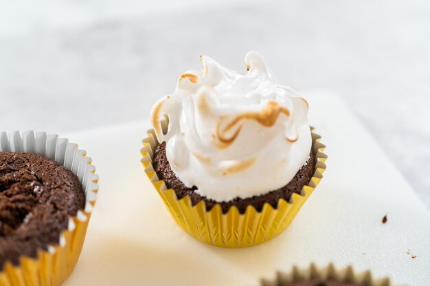 Frosting s'mores cupcakes with white meringue frosting.