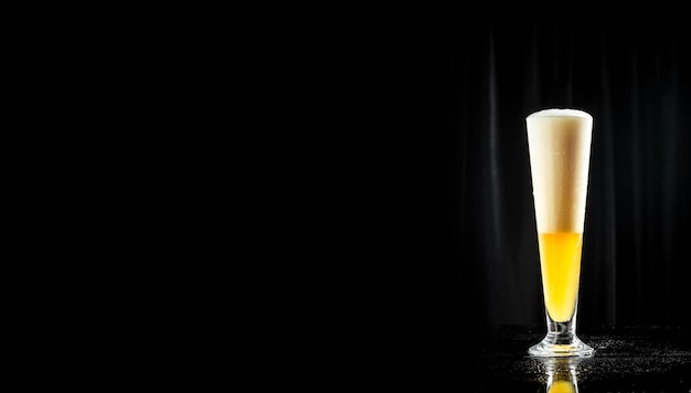 Frosty glass of beer with bubbles and thick white foam on black background banner menu recipe place for text