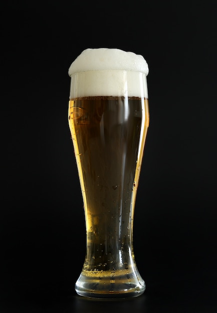 Frosty glass of cold golden beer with bubbles on the black background. Drinking alcohol on party, holidays, Oktoberfest or St. Patrick's Day