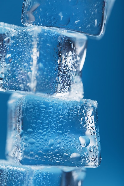 Frosty ice cubes in the form of a tower on a blue background.