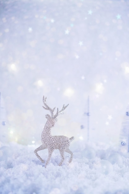 Frosty winter wonderland with toy deer, snowfall and magic lights.  Christmas greetings concept