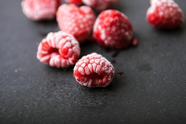 Froszen raspberry on black wooden background