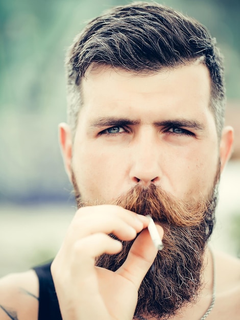 写真 ひげの口ひげと白髪のスタイリッシュなヒップスター男性喫煙タバコ屋外クローズアップと眉をひそめたハンサムなひげを生やした男