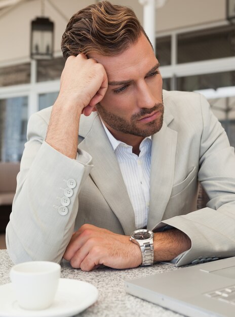 Frowning businessman looking at his laptop