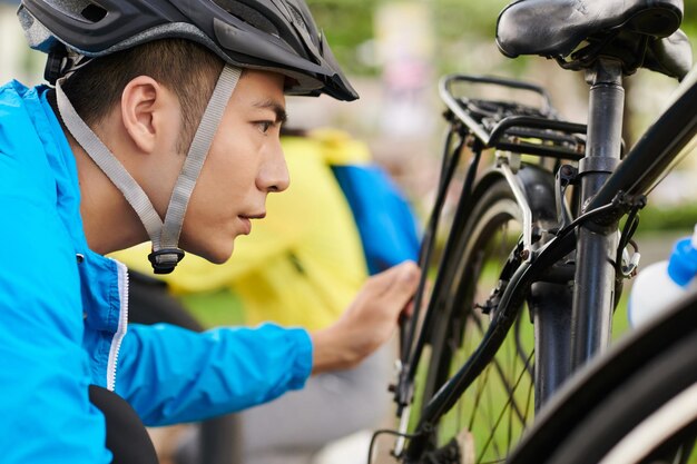 Ciclista accigliato che controlla la bicicletta