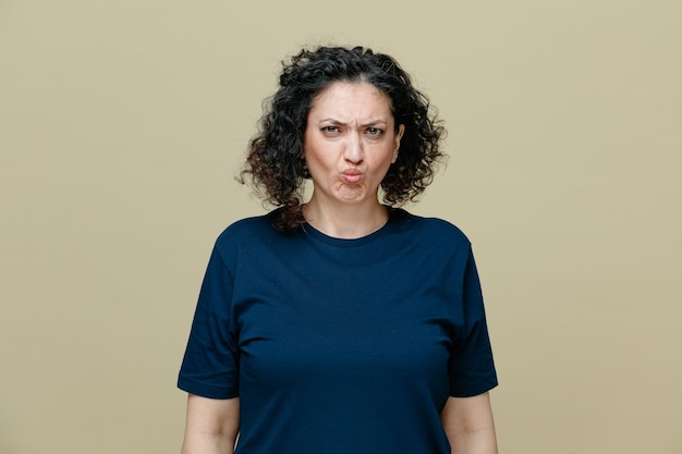 Frowning middleaged woman wearing tshirt looking at camera isolated on olive green background