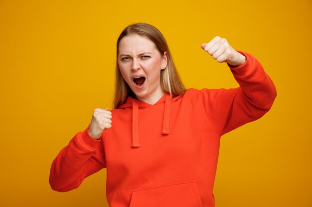 Frowning young blonde woman doing boxing gesture 