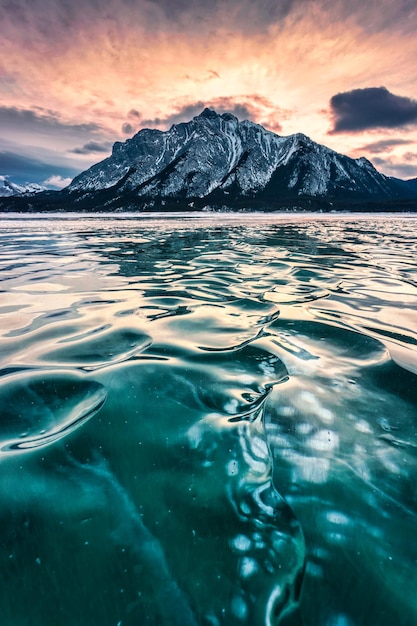 Frozen Abraham Lake with rocky mountains and natural bubbles frost in the morning on winter at Banff national park