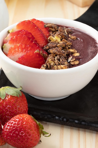 Frozen acai with strawberry and granola in a white bowl