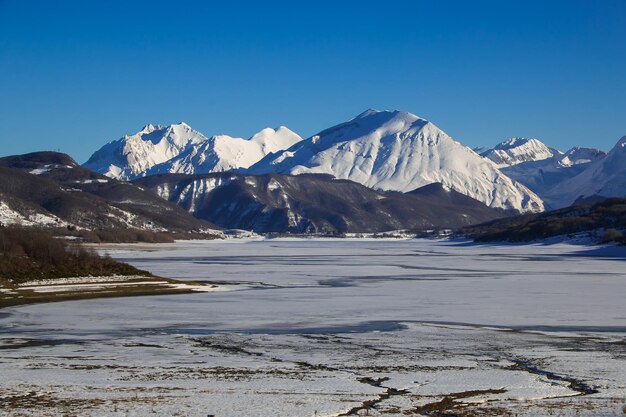 Frozen artificial dam of camposto with high mountains in the background abruzzo