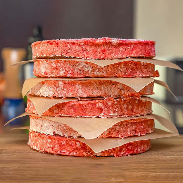 Frozen beef burger patties are placed on a wooden cutting board before cooking. Freezing in the freezer.