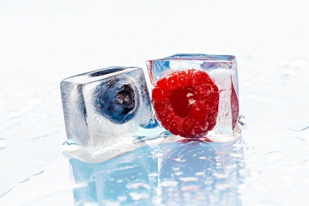 Frozen berries in ice cubes on pink