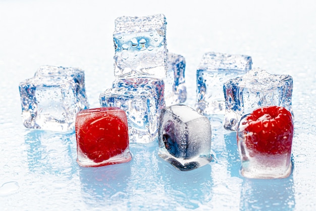 Photo frozen berries in ice cubes on pink