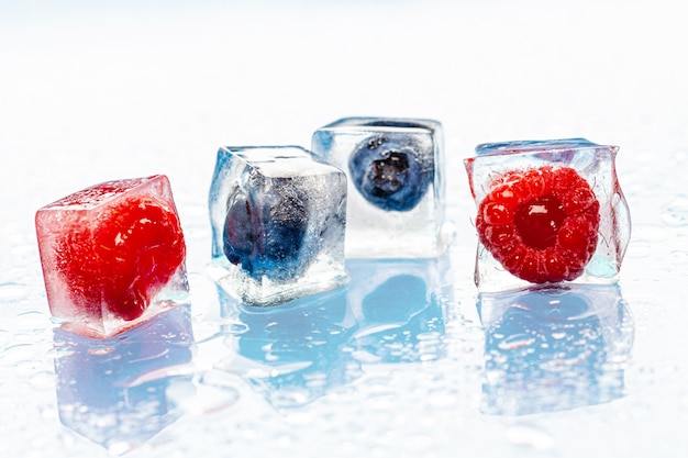 Frozen berries in ice cubes on pink