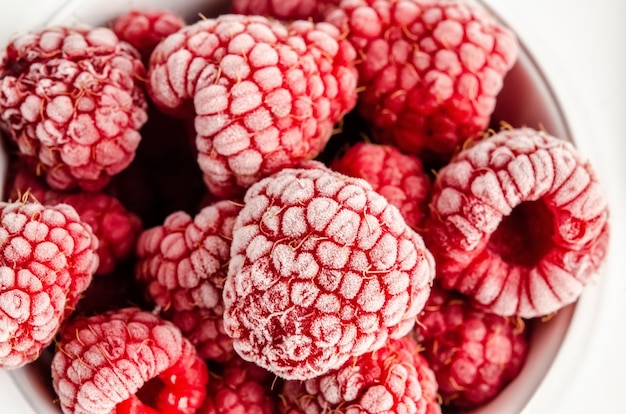 Frozen berries and raspberries on a white surface