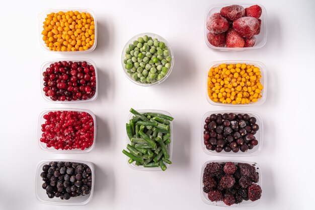 Frozen berries and vegetables in plastic boxes isolated on white