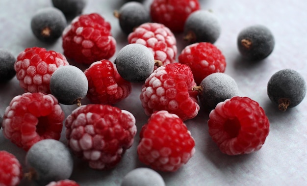 Frozen berry black currant and raspberry with frost on a lilac\
background