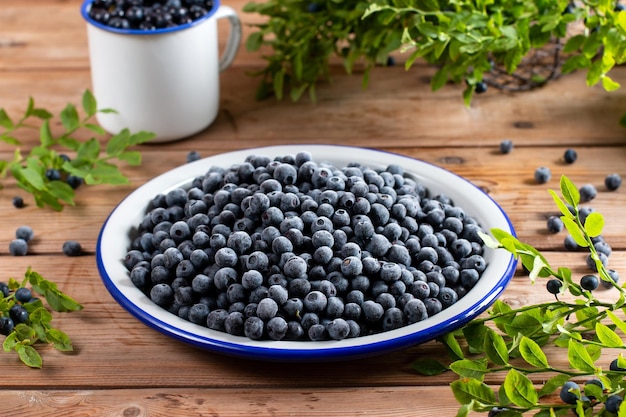 Frozen blueberries in a metal bowl on wooden table