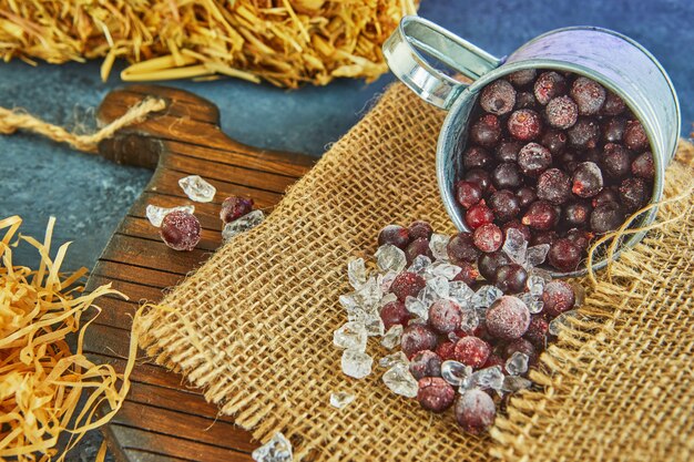 Frozen Blueberries with ice in a tin mug on sacking and hay on a purple background