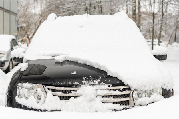 Frozen car covered with snow on a winter day windshield and hood in snow