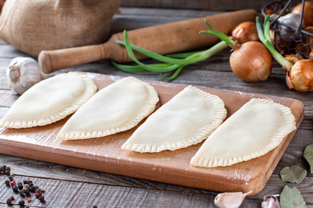 Frozen chebureks on a wooden background