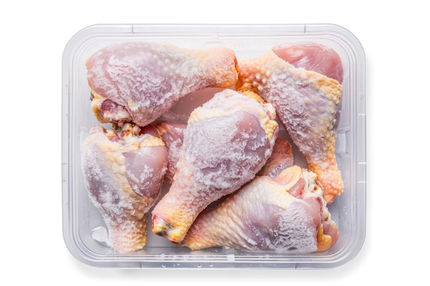 Photo frozen chicken drumsticks in plastic container on white background