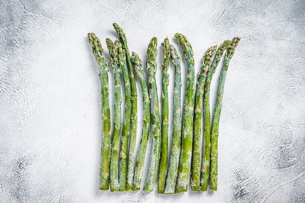 Frozen cold asparagus on a old kitchen table. White background. Top view.