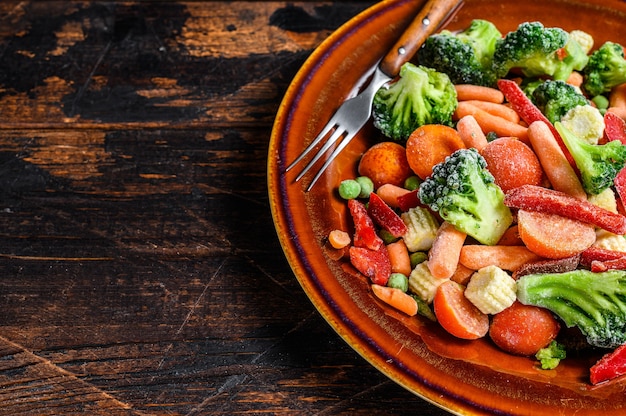 Verdure tagliate congelate, broccoli, peperoni, pomodori, carote, piselli e mais su un piatto