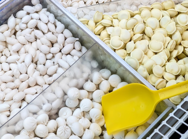 Frozen dumplings sold by weight in a refrigerator container on a store counter