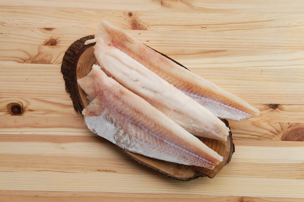 Frozen fillet of pangasius on wooden table