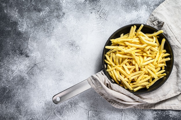 Frozen French fries in a frying pan. 