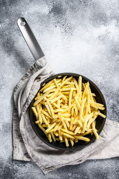 Frozen French fries in a frying pan. 