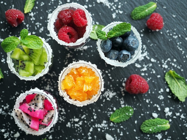 Frutta e bacche congelate con zucchero e foglie di menta in bicchieri