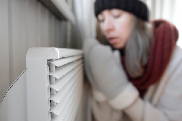 Photo frozen girl wearing a sweater freezing for winter cold and warming up hands over electric heater