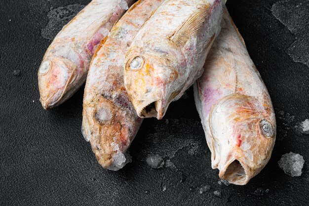 Frozen Goatfish raw fish set, on black dark stone table background