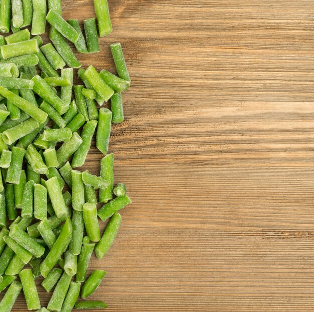 Photo frozen green beans on wood table top view